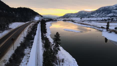 Sonnenuntergang-über-Dem-Thompson-River-Und-Highway-1-In-Kamloops,-BC,-Mit-Schneebedeckten-Bergen-Im-Hintergrund