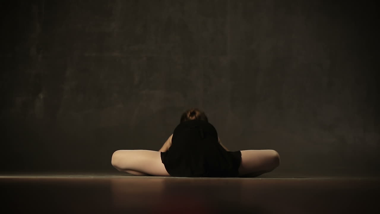 Young incredibly beautiful girl ballerina posing and dancing in a black studio