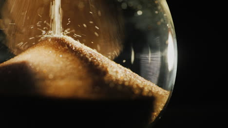 slow motion video of round hourglass flask where grains of sand fall