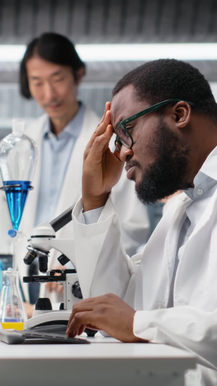 Vertical video Laboratory scientist squinting eyes at computer monitor, thinking