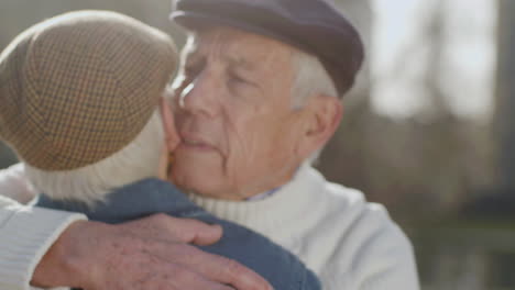 close up of a lovely senior man in grey beret embracing his wife outdoors on autumn day in park