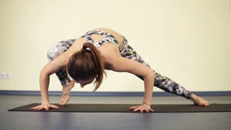 young sportive woman stretching out the entire body while standing in a yoga asana that requires strong arms.