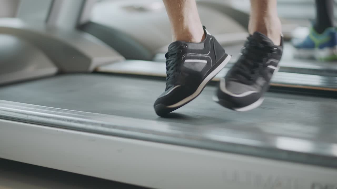 Closeup feet moving on treadmill in fitness gym.