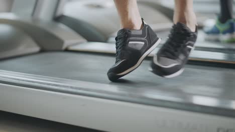 closeup feet moving on treadmill in fitness gym.