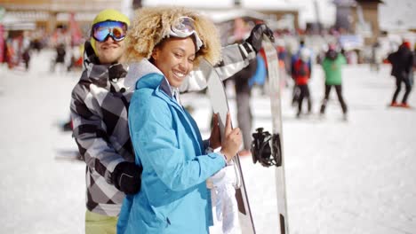 man flirting with woman holding snowboard