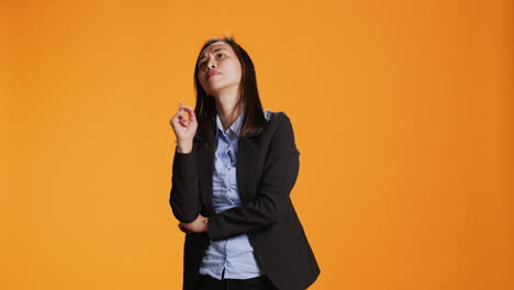 mujer de negocios pensativa posando sobre un fondo naranja