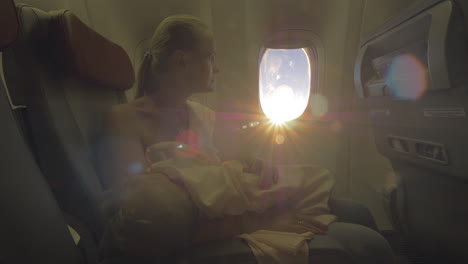 woman nursing baby daughter in the airplane view in bright sunlight