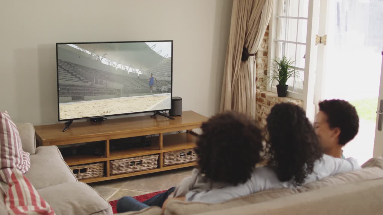 Composizione: famiglia felice seduta a casa insieme che guarda l'atletica del salto in lungo in TV.