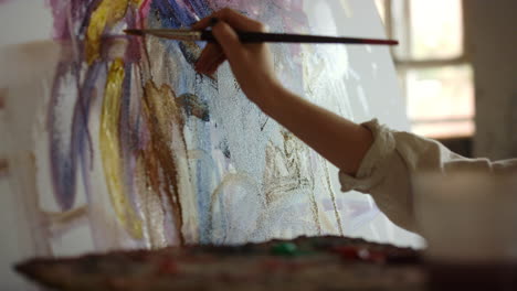 Female-painter-holding-paintbrush-in-studio.-Woman-creating-picture-indoors.