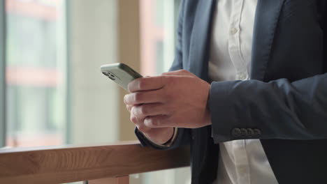 the hands of a businessman in a blue blazer consults his smart phone and write on it 2