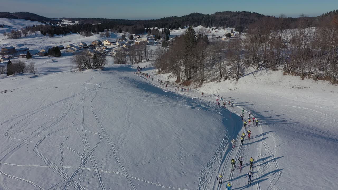 Folla di atleti sciatori a una gara di sci in una foresta invernale innevata, in una giornata di sole splendente in Francia.