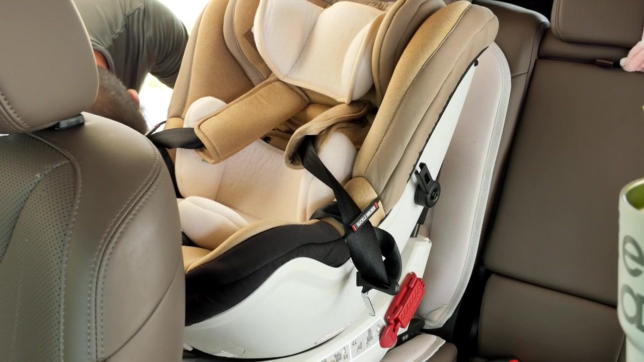 Un hombre asegura cuidadosamente una silla de coche para bebé en el asiento trasero de un vehículo. Ideal para guías de paternidad o tutoriales de seguridad automotriz.