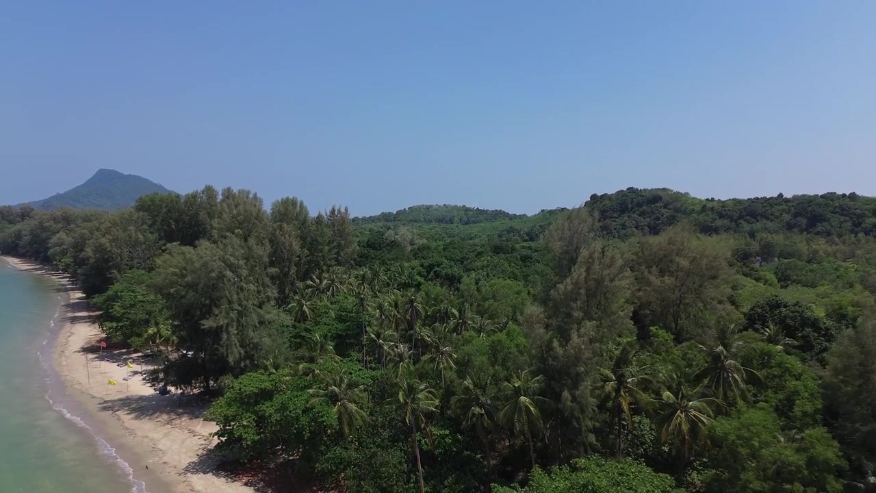 Volo di drone aereo sopra palme lussureggianti che rivela una spiaggia tropicale appartata con acqua turchese sull'isola di Koh Jum, Thailandia. Panoramica costa paradisiaca remota nel Mare delle Andamane senza persone