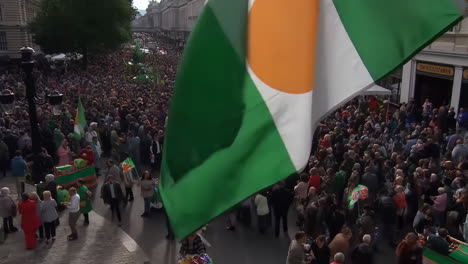 large crowd attends irish parade with waving flags