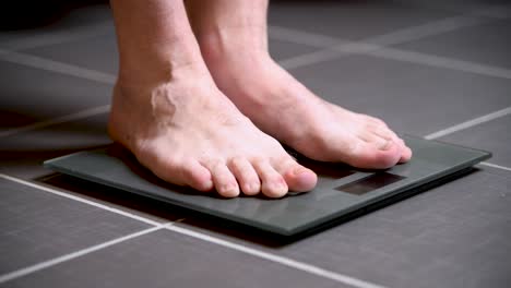 man steps on a home scale, checks his weight, and steps back off