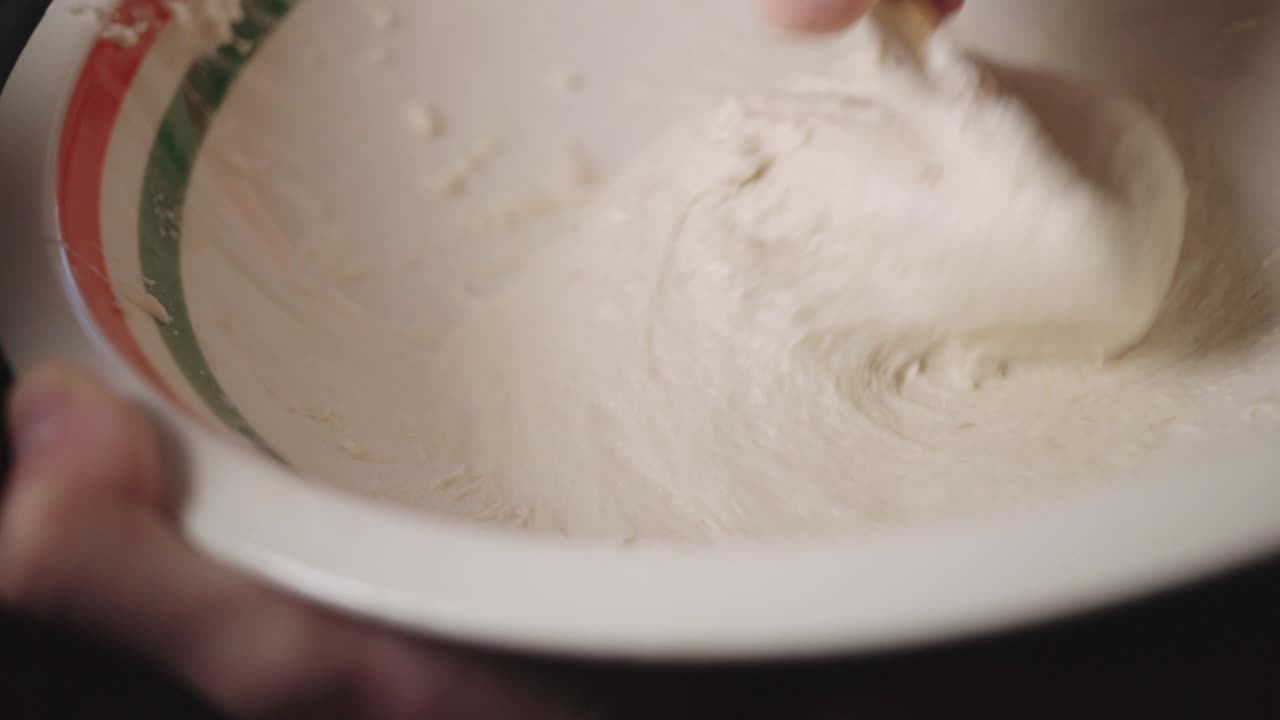 Hand Mixing A Sticky Flour On A Bowl With A Spoon - Closeup Shot