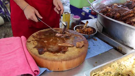 vendor portions stewed meat at outdoor stall.