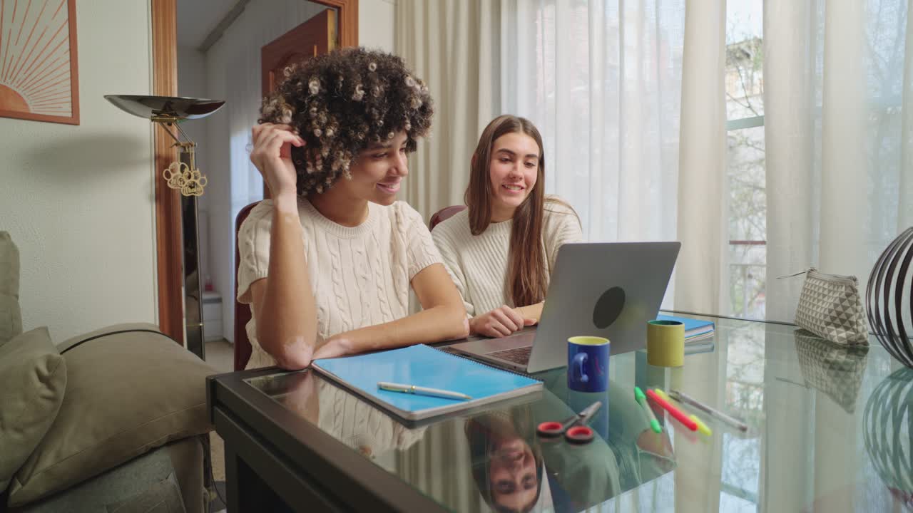 Two women working at a desk with a laptop