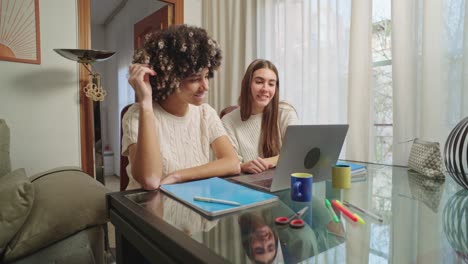 two women working at a desk with a laptop