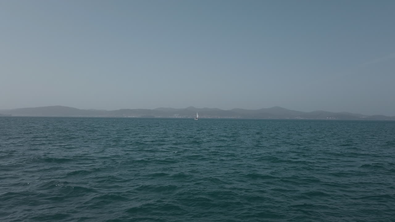 범선은 크로아티아 섬 사이의 아드리아 해를 항해할 때 프레임을 가로지릅니다.