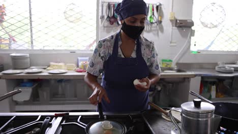 chef femenina étnica fritando platos en la cocina del restaurante