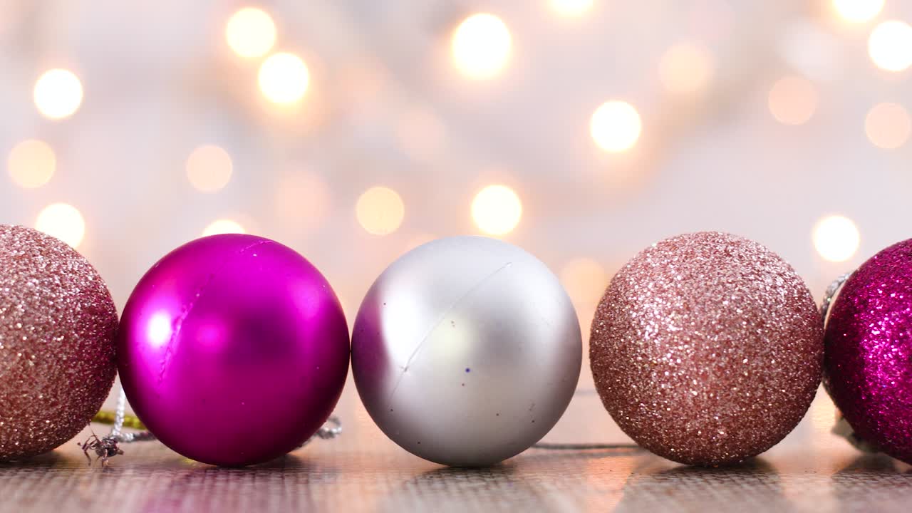 luces navideñas parpadeantes y brillantes adornos rosados, plateados y dorados ordenados en línea