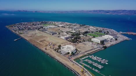 4k aerial drone view of treasure island san francisco bay area surrounded by turquoise blue ocean sea water waves camera look down and hold