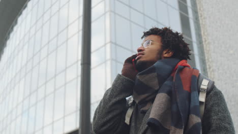 man talking on phone in front of modern building