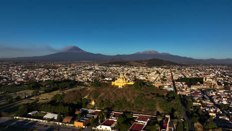 aerial: vibrant church on the cholula pyramid, sunny evening in puebla, mexico