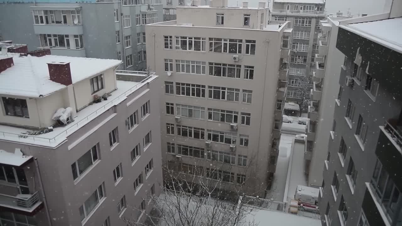 A big snow storm, called Filomena, falls over the large buildings in the city.Aerial view. Beautifully snow falling shot over city in evening time.