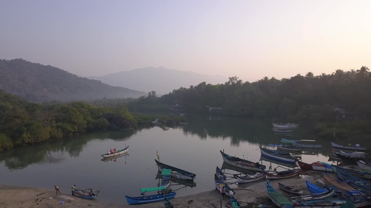 barcos de madera atracados en un lago tranquilo con el reflejo de los árboles durante una mañana brumosa en la playa de palolem, canacona en el sur de goa, india