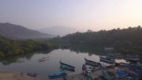 wooden boats moored on calm lake with trees reflection during misty morning at palolem beach, canacona in south goa, india