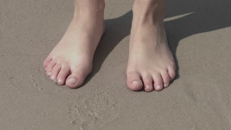 A human with bare feet standing in his shadow alone at the ocean edge