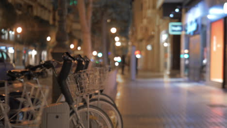 walking by bike sharing station in night city valencia