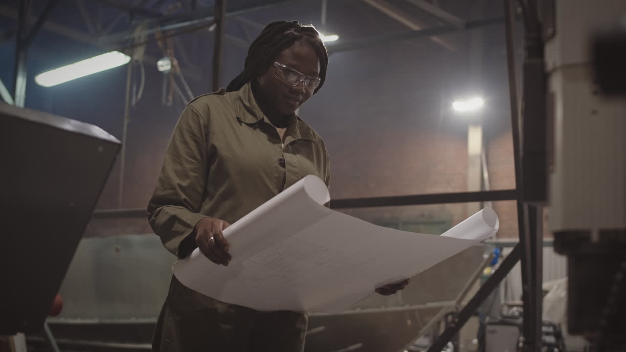 Engineer Inspecting Blueprints in Factory