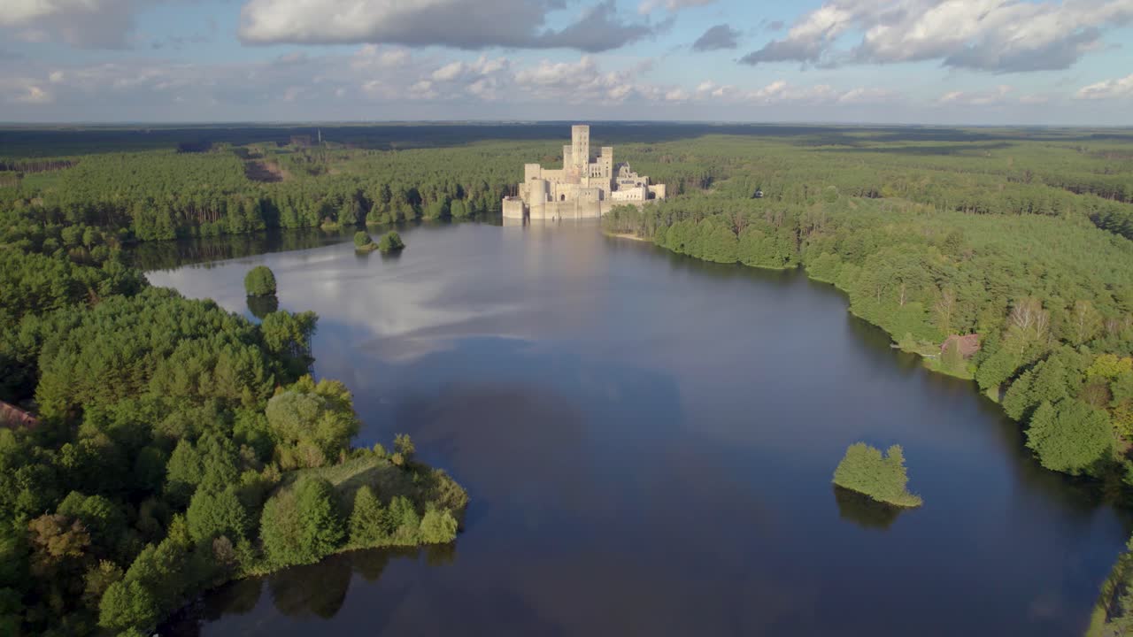 Aerial wide dolly shot of the Castle of Stobnica, Poland - a big tourist attraction built on an artificial island on a lake in the middle of an unhabituated forest