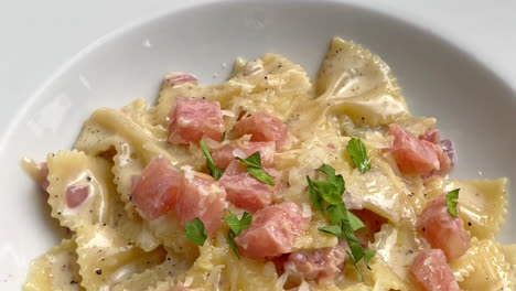 carbonara farfalle pasta with ham sausage on white plate