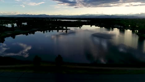 Atemberaubende-Herrlichkeit-In-Diesem-Sonnenuntergang-Mit-Wolken,-Die-Sich-In-Seen-Mit-Den-Felsigen-Bergen-Im-Hintergrund-Spiegeln