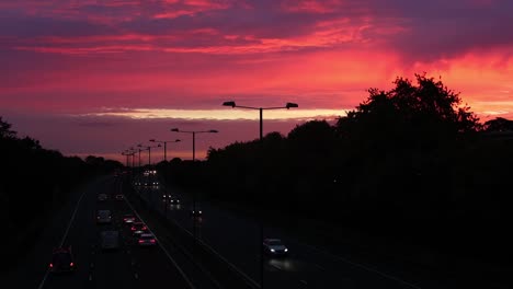 early morning highway traffic, with a colourful sunrise in the background