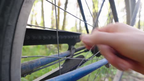 Man-wiggling-a-broken-spoke-on-a-bike-wheel