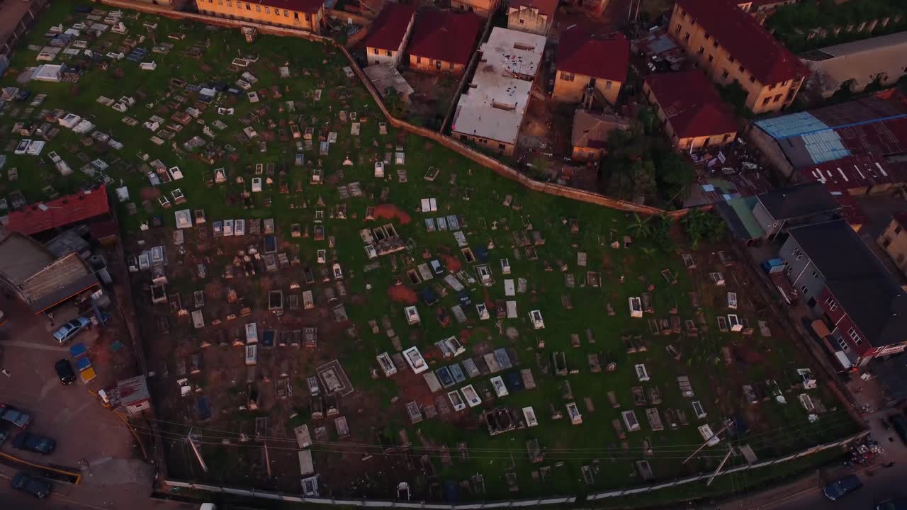 Drone video captures a solemn cemetery at dusk, with rows of graves and tombstones casting shadow under dim light at countryside, Nigeria. Peaceful aerial footage evokes a reflective mood of deceased