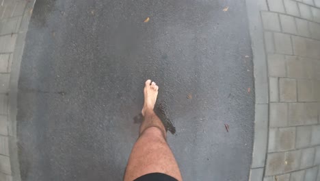 hombre corriendo descalzo con pantalones cortos corriendo por la carretera de asfalto usando go pro en el cuerpo