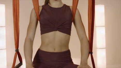 fit woman doing yoga at fly yoga studio. girl practicing yoga with hammock