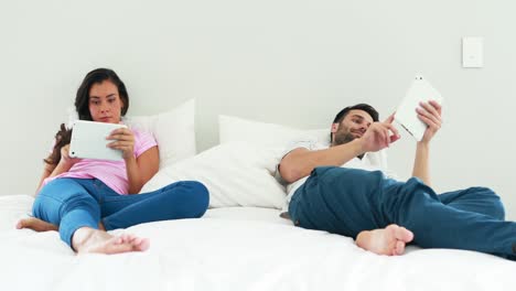 couple using digital tablet on bed in the bedroom