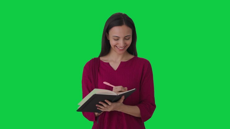 feliz maestra india tomando asistencia en la pantalla verde de la escuela