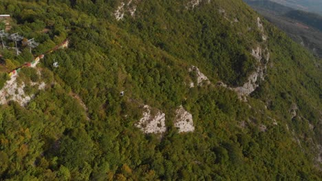 Slow-aerial-tracking-shot-over-two-gondolas-against-green-mountains