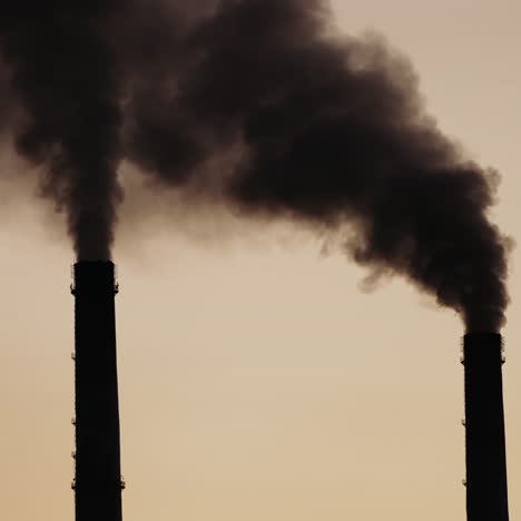 black dense smoke comes from industrial pipes. chemical smoke pollute the atmosphere of the evening sky. close-up.