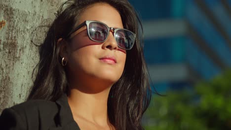 facial close up of a latina girl in the city with her hair blowing in the wind on a sunny day