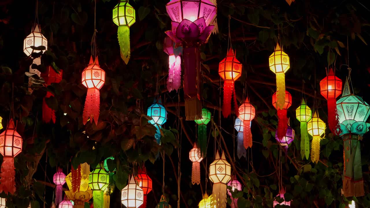 Hanging paper lanterns glow in multiple colors as part of a nighttime festival in Thailand