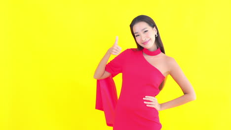 프레임 오른쪽에 있는 예쁜 젊은 여성이 성공을 위해 엄지손가락을 치켜들며 미소 짓고 있습니다.
